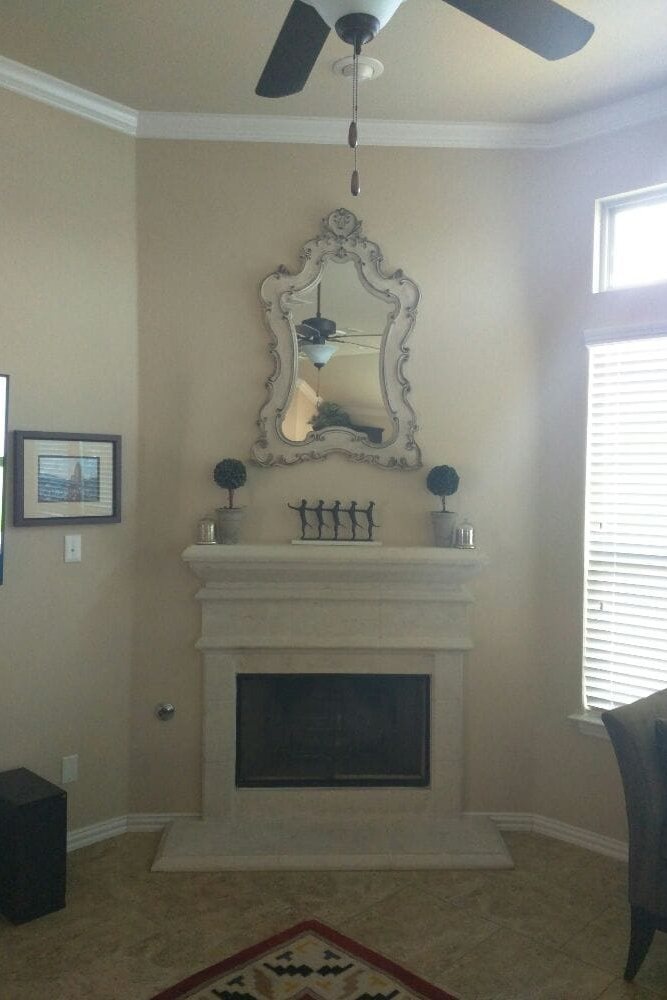 Ornate mirror hung centered over a corner fireplace