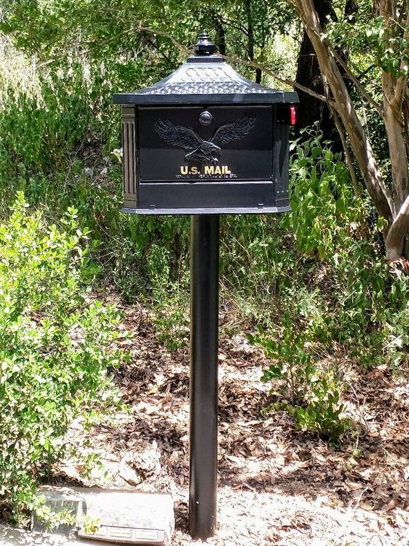 Black cast mailbox on a plumb steel post